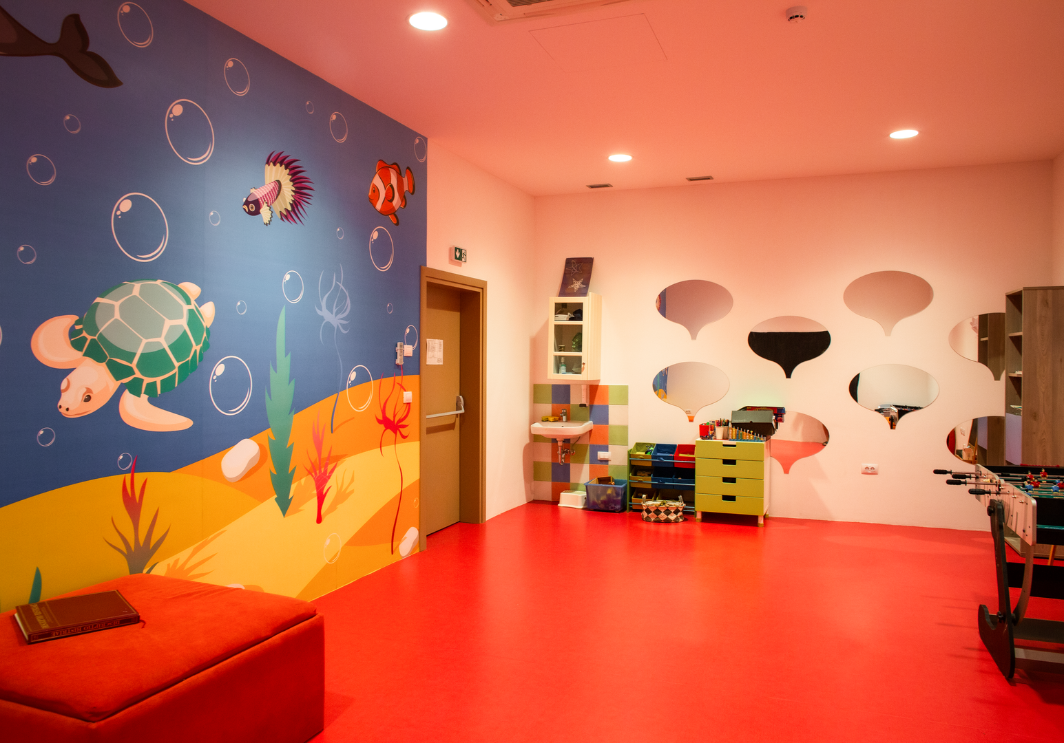 Bunt gestaltetes Spielzimmer für Kinder mit Wanddekorationen und Spielmöglichkeiten.