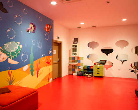 Bunt gestaltetes Spielzimmer für Kinder mit Wanddekorationen und Spielmöglichkeiten.
