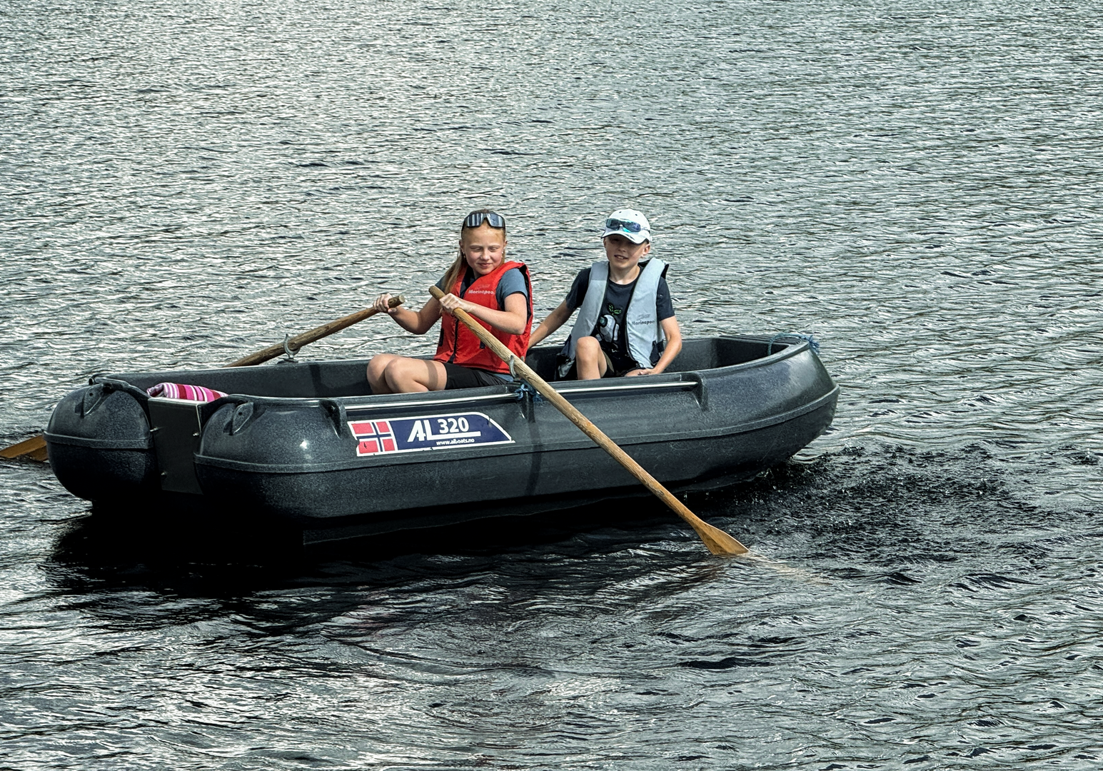 Familie fährt mit einem Paddelboot auf einem See.