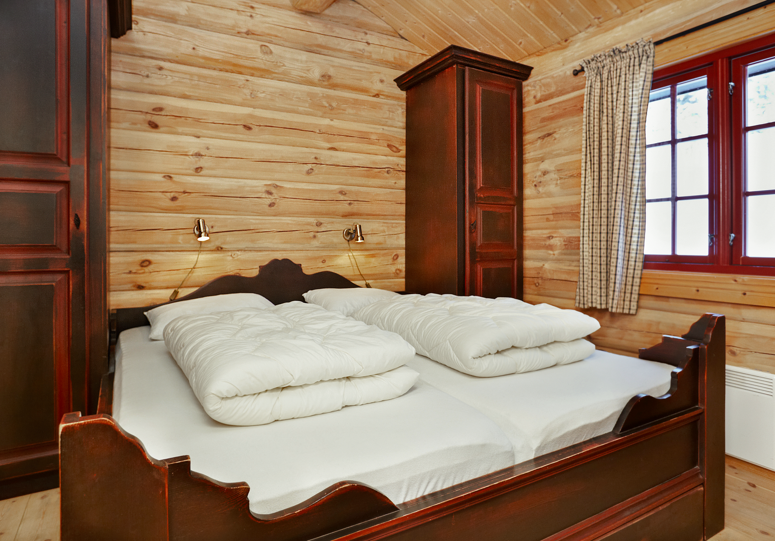 Schlafzimmer mit Doppelbett, Holzvertäfelung und rustikaler Einrichtung.