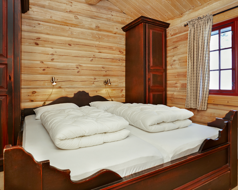 Schlafzimmer mit Doppelbett, Holzvertäfelung und rustikaler Einrichtung.