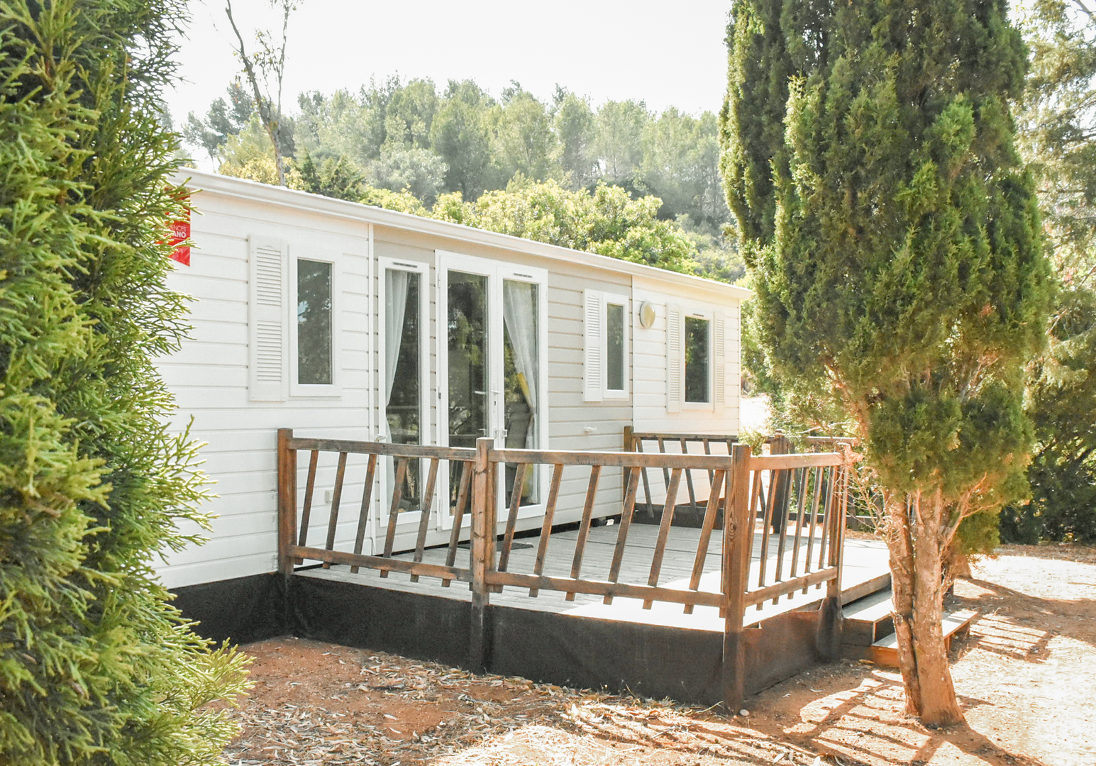 Mobilheim mit Terrasse und Sitzmöbeln im Grünen