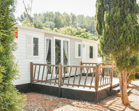 Mobilheim mit Terrasse und Sitzmöbeln im Grünen