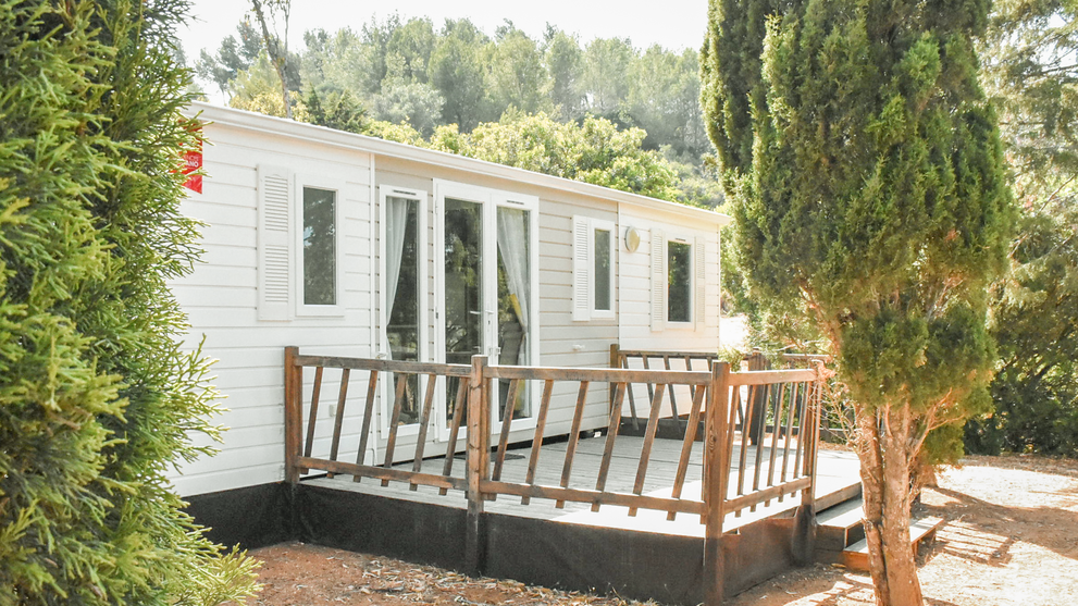 Mobilheim mit Terrasse und Sitzmöbeln im Grünen